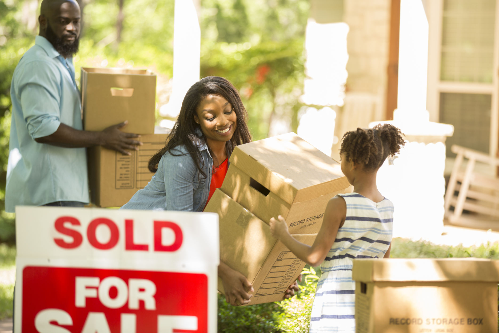 A sold sign and a family moving cardboard boxes