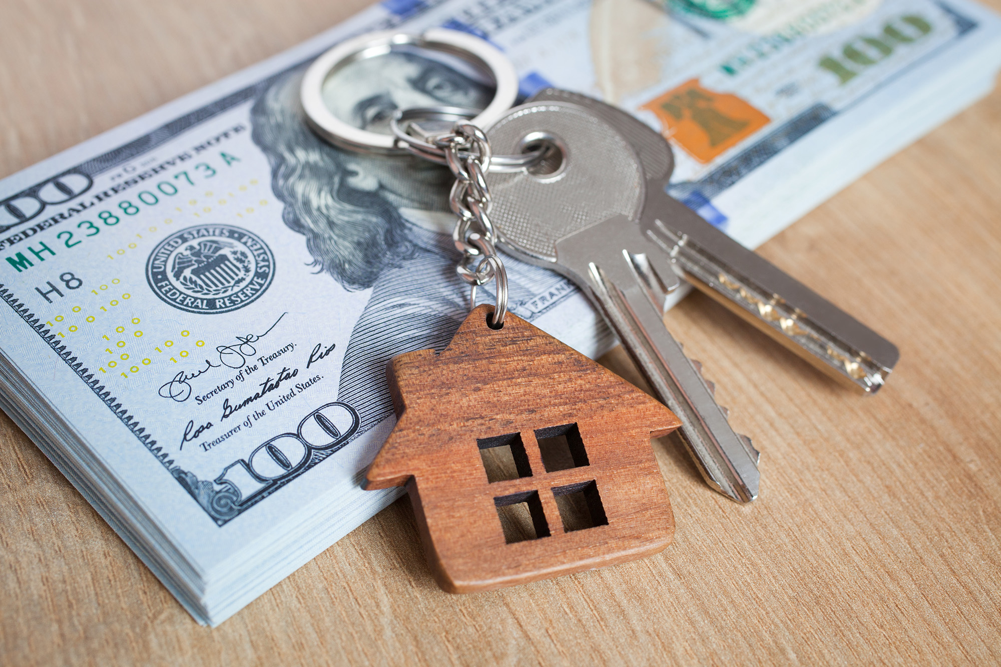 A close-up of a stack of money with keys and keychain