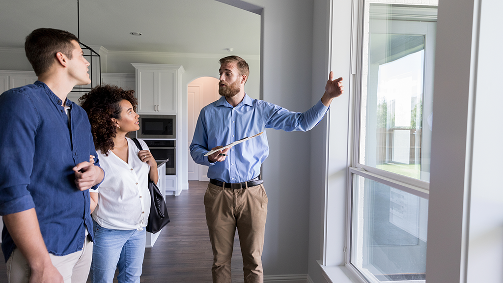 Business person shows couple around the inside of a home