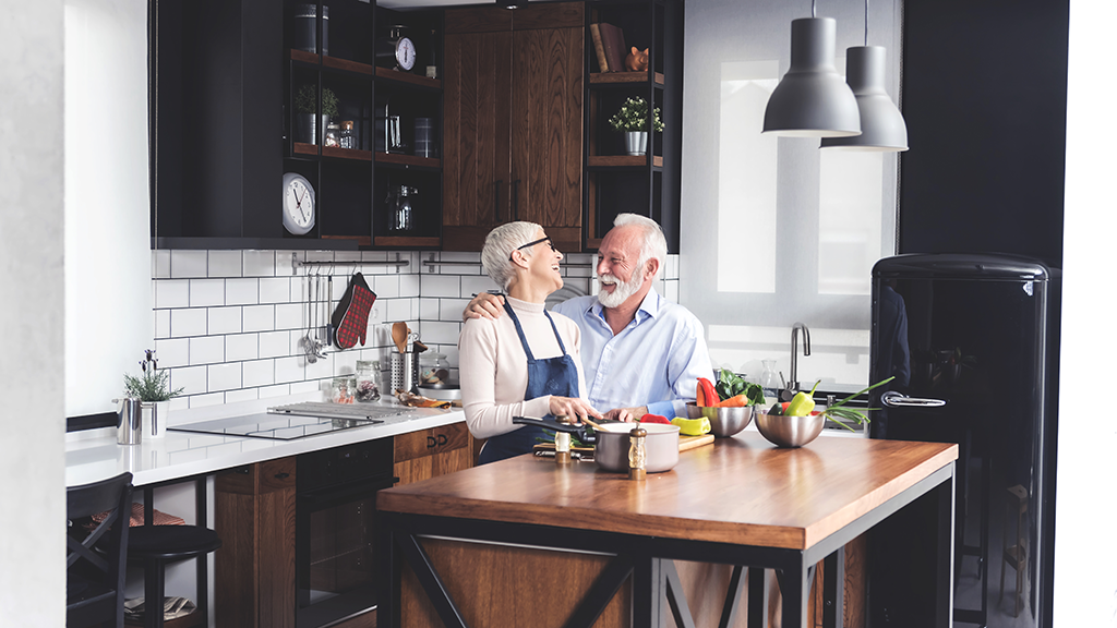 Older couple in a kitchen looking at each other with smiles on their faces