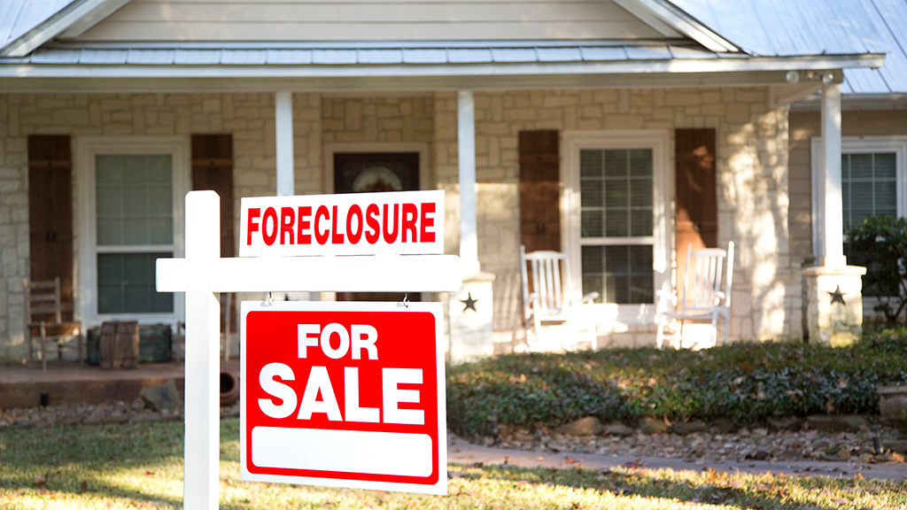 A foreclosure sign in front of a ranch style home