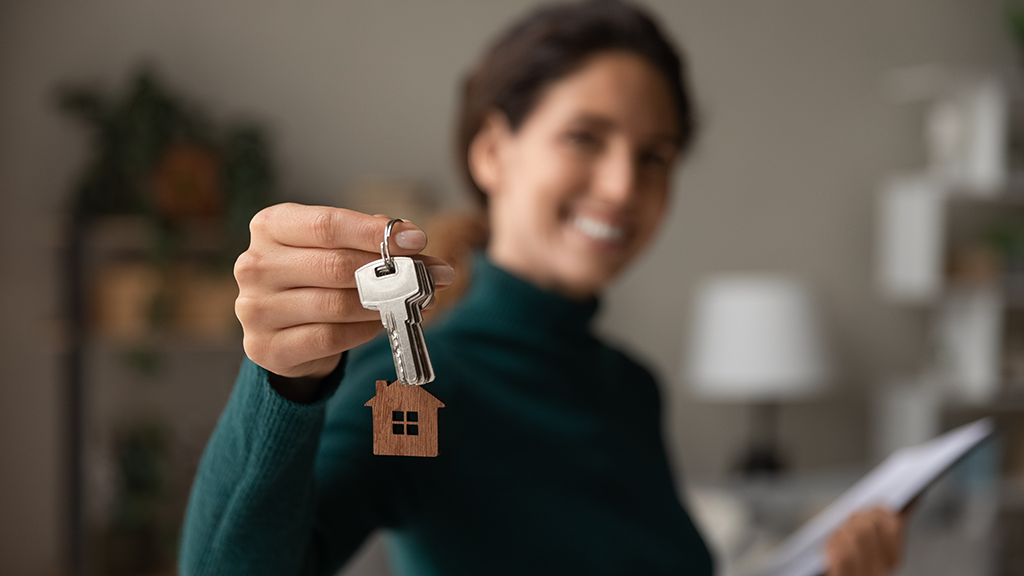 A woman holds a set of keys with a small house keychain