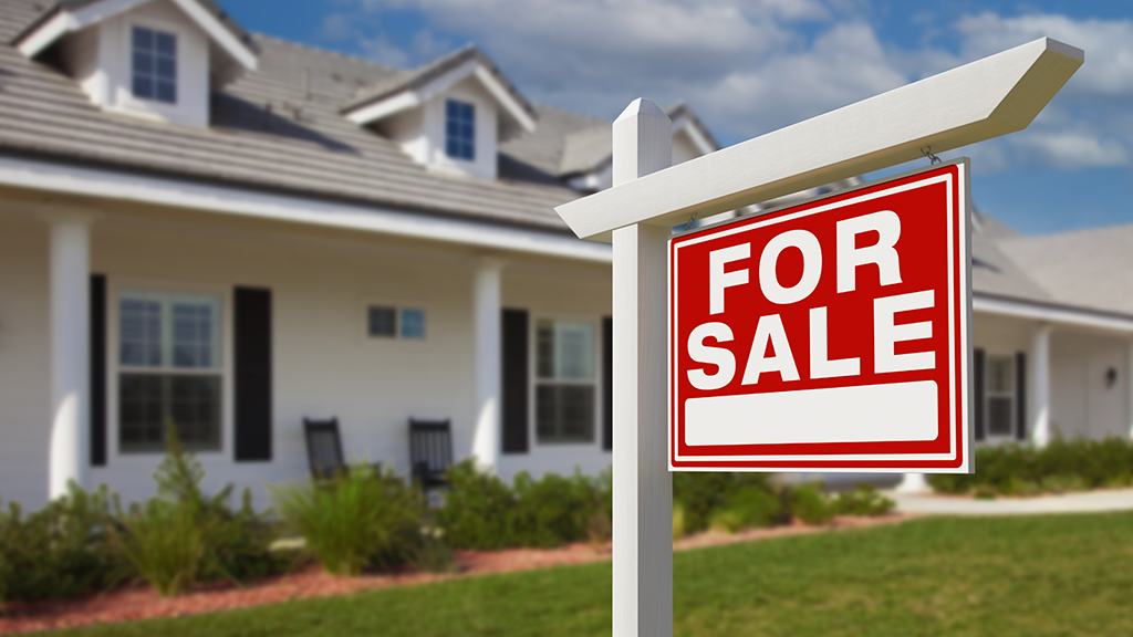 A for sale yard sign in front of a house