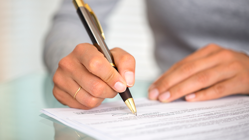 Close-up of person signing a document