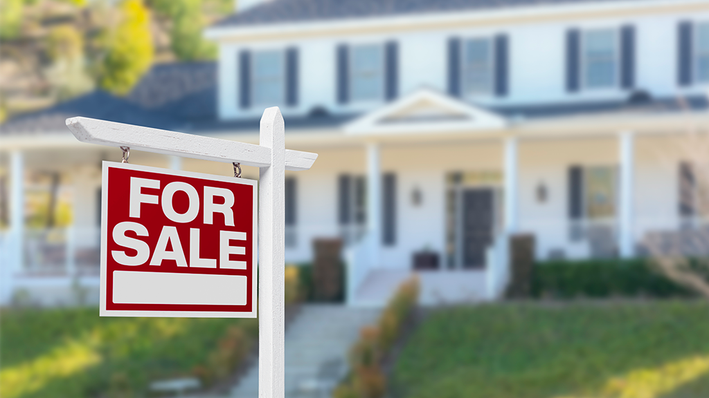 For sale sign in front of a two-story house