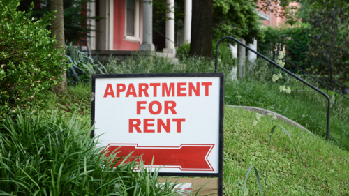 An apartment for rent sign in a yard