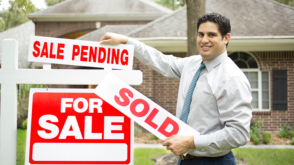 An agent changing a yard sign from sale pending to sold