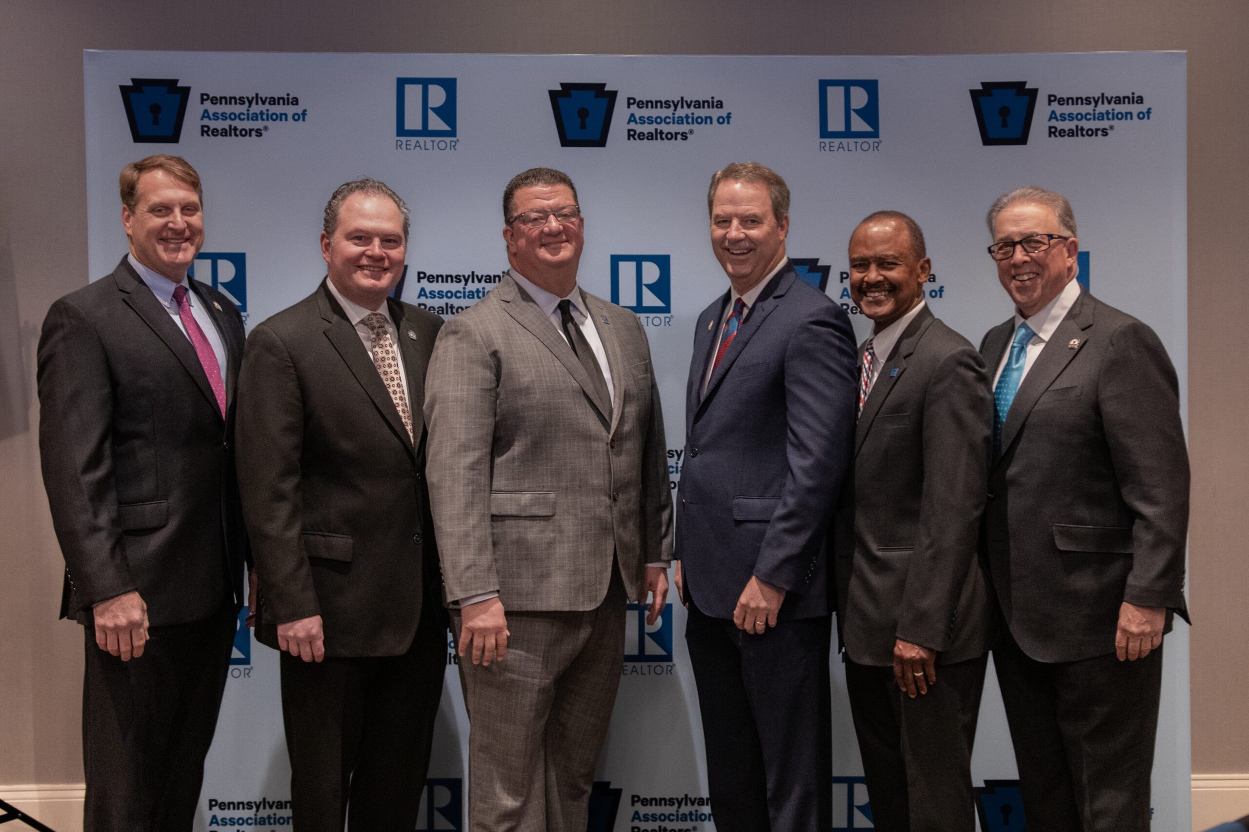 Ken Enochs, Christopher Beadling, Al Perry, David Kent, Preston Moore, Bill Lublin stand in front of a blue backdrop at the RPAC Awards Luncheon